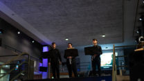 Three RNCM brass students dressed in black prepare to perform. 